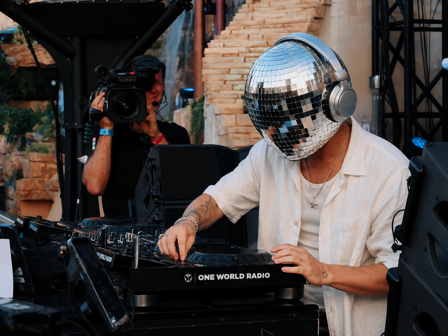 STARBØY DJing beside a camera operator at an outdoor stage
